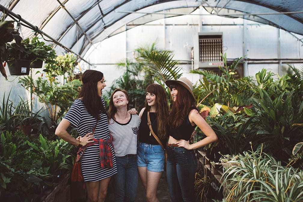 friends girlfriends greenhouse plants laughing girls trip road trip four group