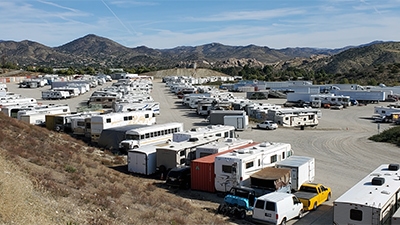 cars trucks RVs and shipping containers on a large sand lot